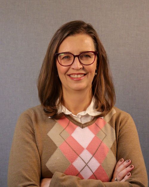A professional headshot of Rachel Zenzinger. She is a smiling woman with shoulder-length brown hair and glasses