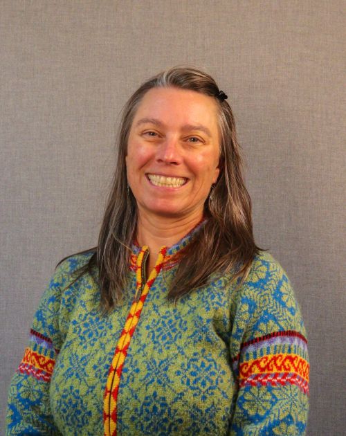 A professional headshot of Monica DeGraff, a smiling woman with long, wavy brown hair with streaks of gray