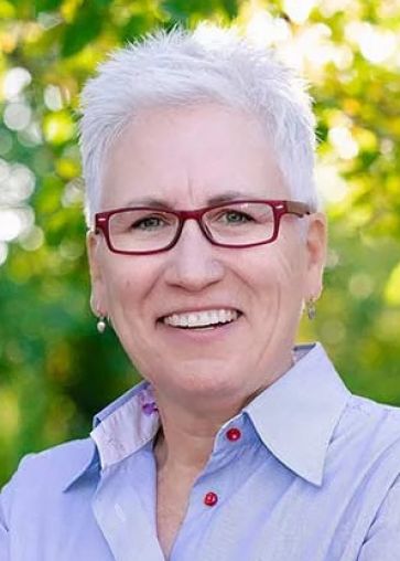 A professional headshot of a smiling woman, Lenya Robinson, standing outdoors.