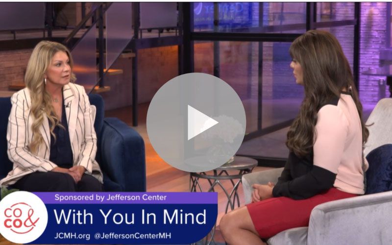 A video thumbnail of a "Colorado and Company" television segment titled "With You In Mind," sponsored by Jefferson Center. On a modern TV set, a female host interviews a woman. A banner at the bottom includes the Jefferson Center logo, website, and social media handle.