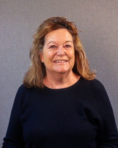 A professional headshot of Tracy Kraft-Tharp. She is a woman with shoulder-length, wavy brown hair, smiling warmly at the camera