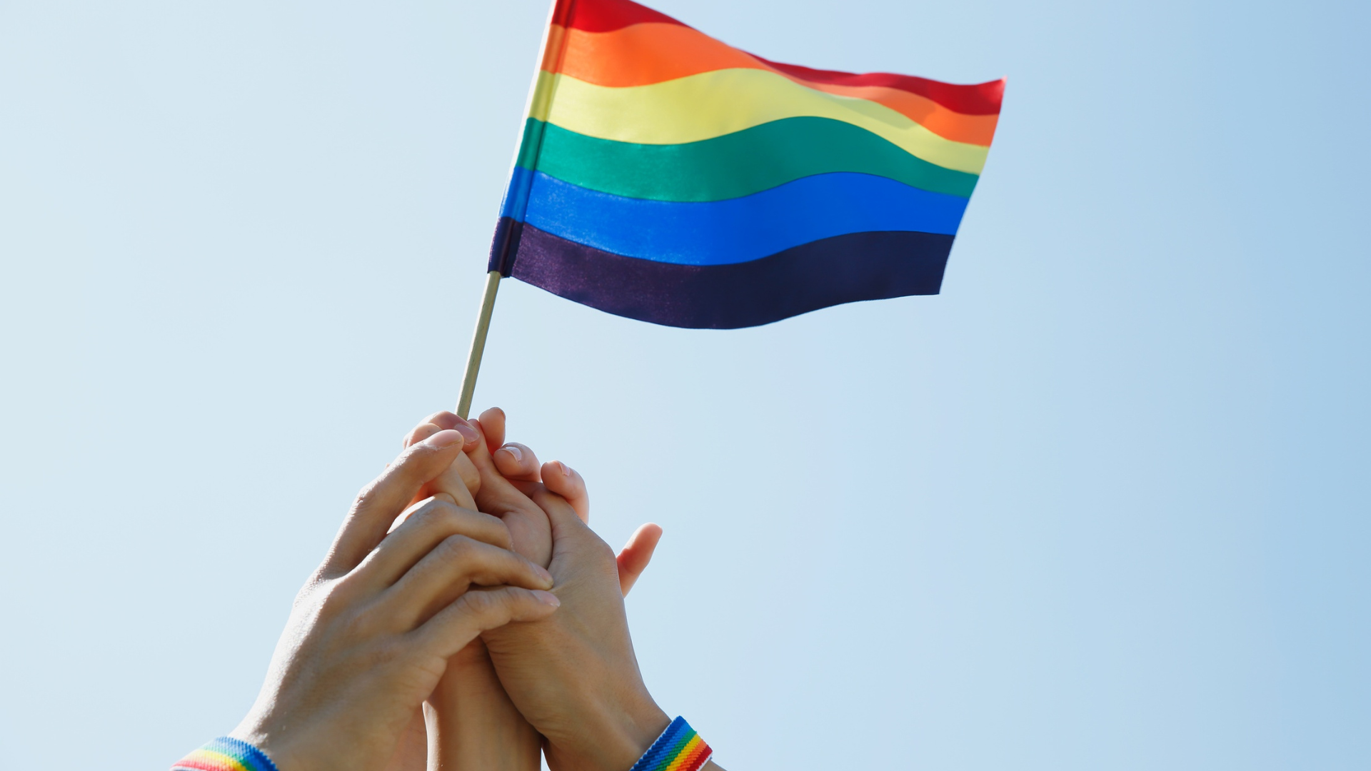 Hands holding up the rainbow pride flag