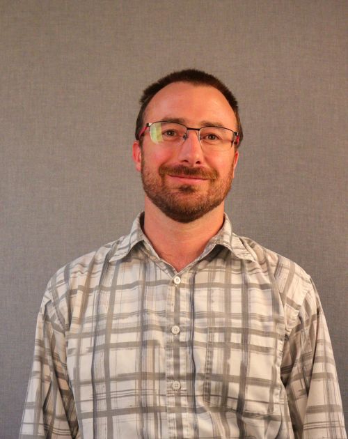 A professional headshot of George Marlin, a man with brown hair, a beard, and glasses.