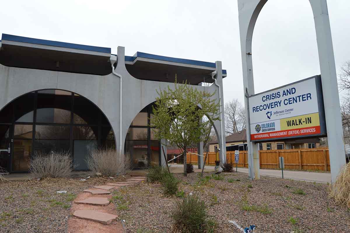 The exterior of the Crisis and Recovery Center on an overcast day. A large sign in the foreground reads "Crisis and Recovery Center" and specifies it offers "Walk-In" and "Withdrawal Management (Detox) Services" as part of Colorado Crisis Services and Jefferson Center.
