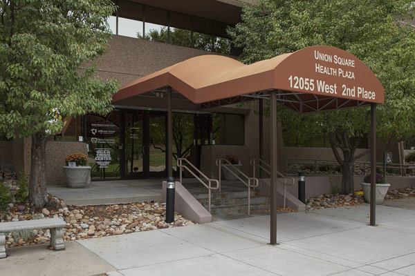 The entrance to the Union Square Health Plaza at 12055 West 2nd Place. A large, brown awning covers the stairway leading to the glass entry doors.