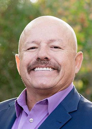 Une photo professionnelle de David Goff, un homme chauve souriant avec une moustache