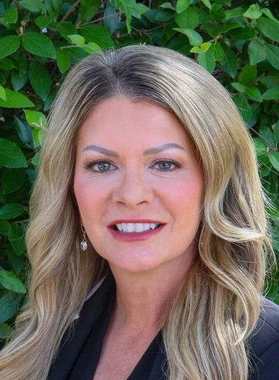 Une photo professionnelle de Sarah Alquist, une femme souriante aux cheveux longs, ondulés et blonds